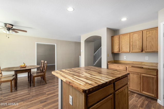 kitchen featuring butcher block countertops, arched walkways, ceiling fan, and dark wood-style floors