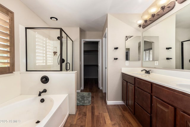 full bath featuring a sink, a garden tub, a shower stall, and wood finished floors