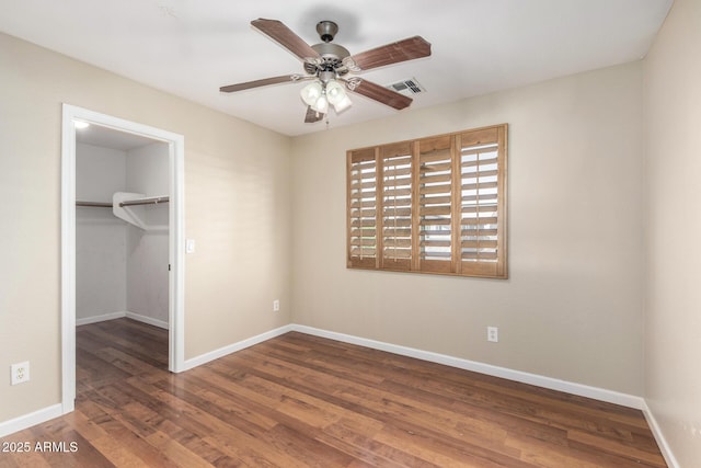 unfurnished bedroom with baseboards, wood finished floors, and a spacious closet