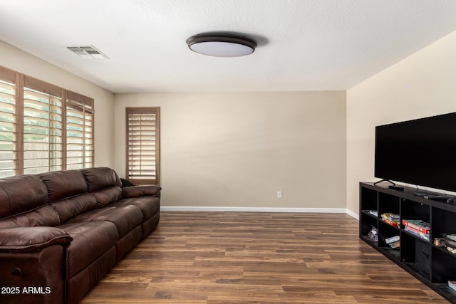 living room featuring visible vents, dark wood finished floors, and baseboards