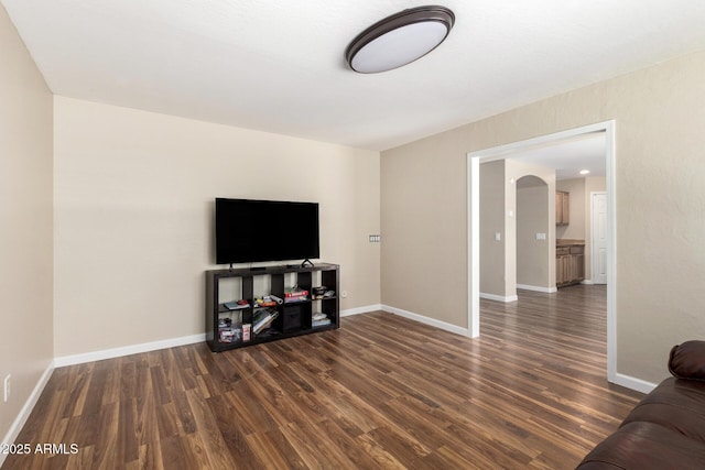 living area with arched walkways, baseboards, and dark wood-style floors