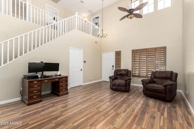 sitting room with a ceiling fan, stairs, wood finished floors, and a towering ceiling