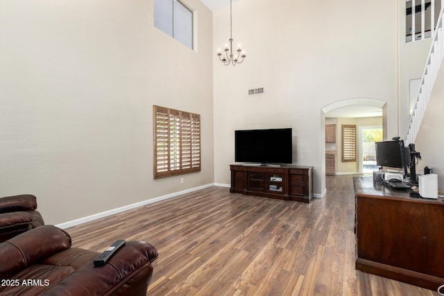 living room featuring arched walkways, visible vents, baseboards, and dark wood-type flooring