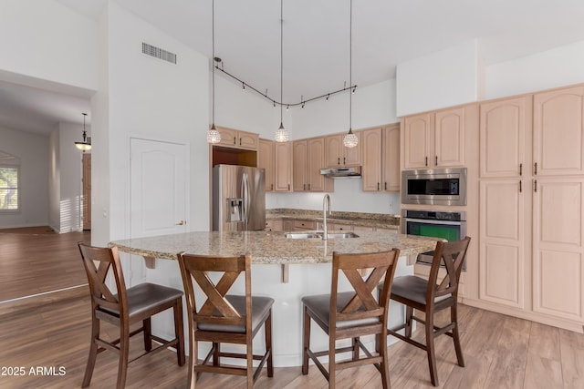 14056 E Desert Cove Ave, Scottsdale, AZ 85259 - kitchen with stainless steel appliances, a towering ceiling, a sink, under cabinet range hood, and a breakfast bar