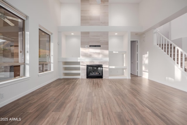 14056 E Desert Cove Ave, Scottsdale, AZ 85259 - unfurnished living room with a high ceiling, wood finished floors, stairs, a fireplace, and a ceiling fan