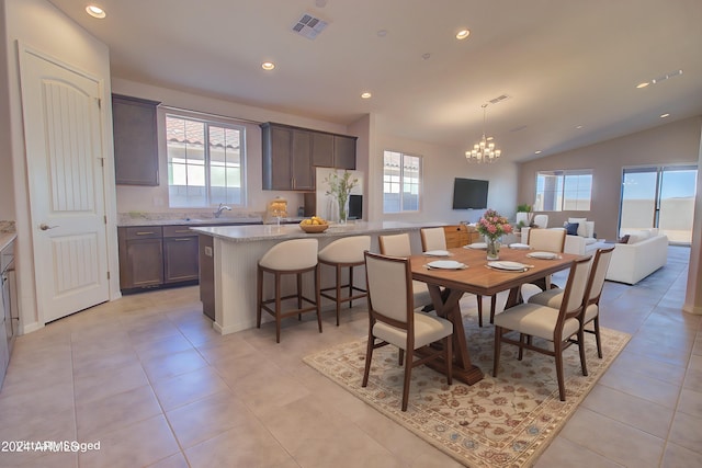 tiled dining space with lofted ceiling, plenty of natural light, and a chandelier