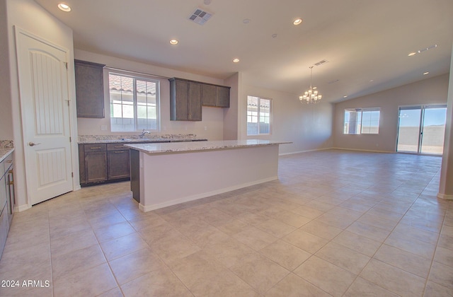 kitchen with a kitchen island, light stone countertops, lofted ceiling, and light tile patterned floors