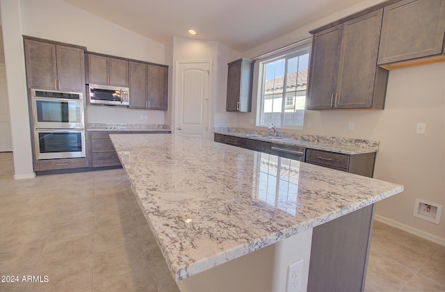 kitchen with appliances with stainless steel finishes, a center island, and light stone counters