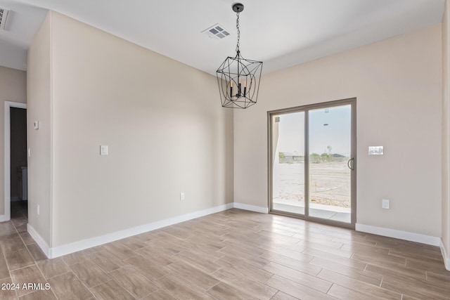 empty room with light hardwood / wood-style flooring and an inviting chandelier