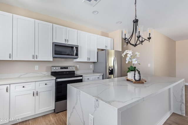 kitchen featuring appliances with stainless steel finishes, white cabinetry, and hanging light fixtures