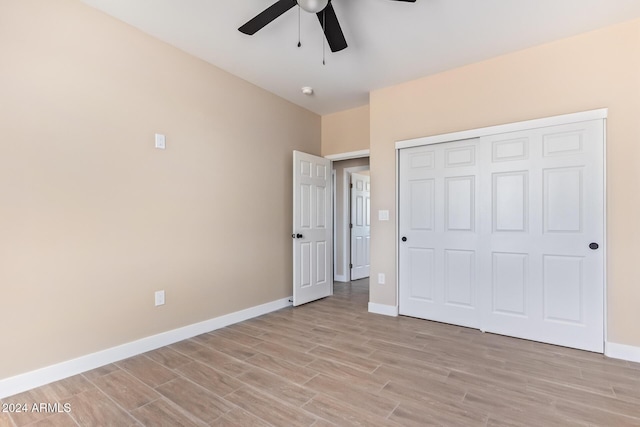 unfurnished bedroom featuring ceiling fan, a closet, and light wood-type flooring