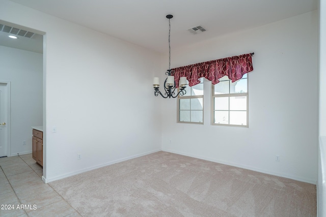 carpeted empty room with an inviting chandelier