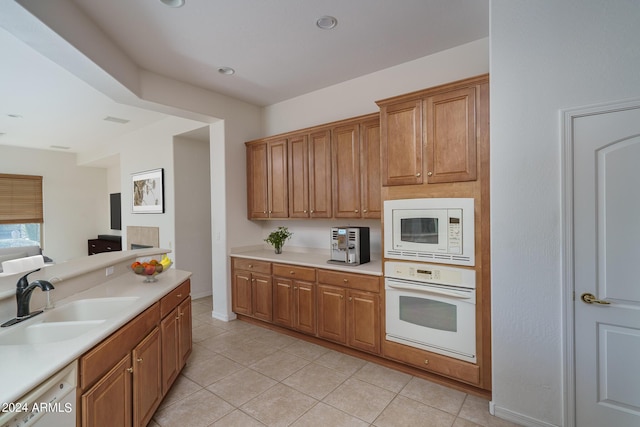 kitchen featuring light tile patterned flooring, white appliances, and sink