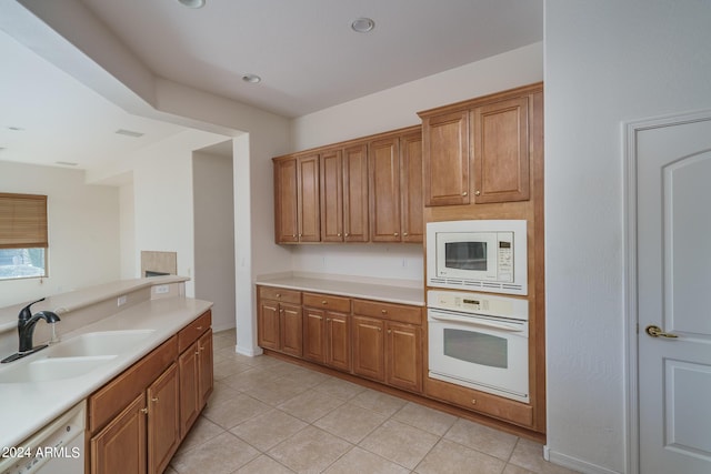 kitchen with sink, light tile patterned floors, and white appliances