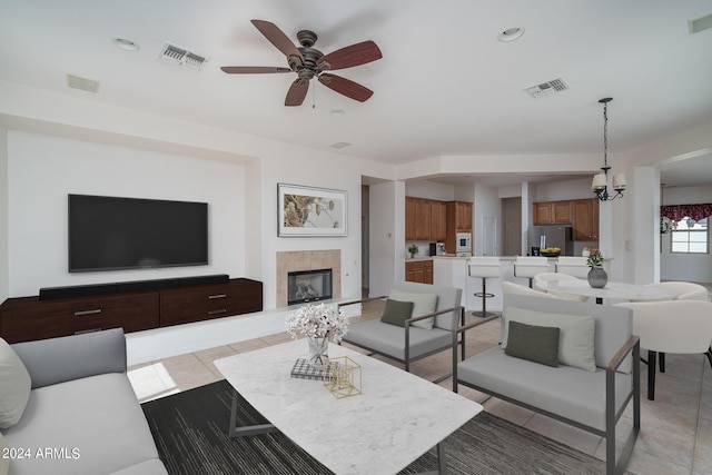 living room with a tile fireplace, light tile patterned floors, and ceiling fan