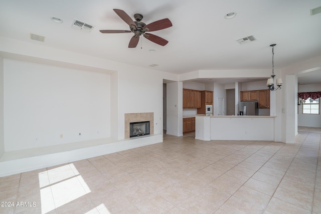 unfurnished living room with a tiled fireplace, light tile patterned floors, and ceiling fan