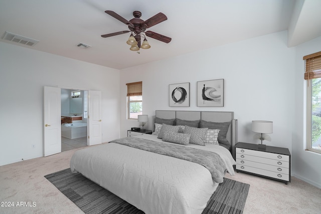 bedroom featuring multiple windows, light colored carpet, ceiling fan, and ensuite bathroom