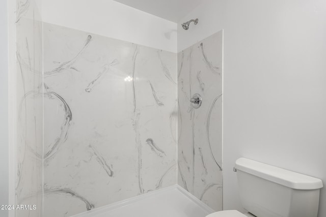 bathroom featuring toilet and a tile shower