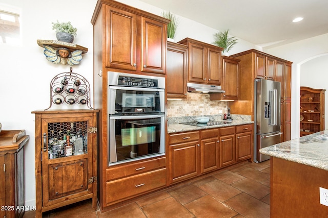 kitchen with light stone countertops, appliances with stainless steel finishes, and decorative backsplash