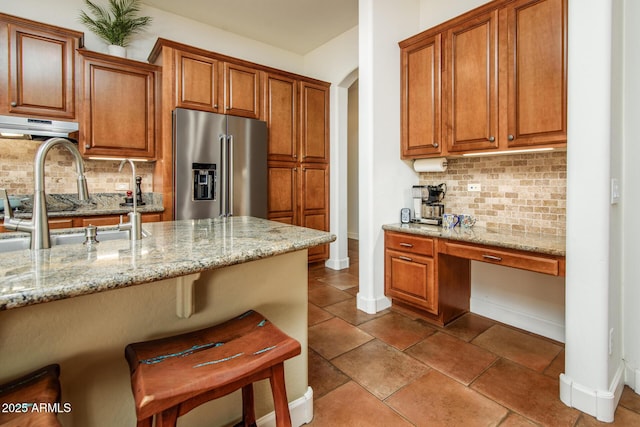 kitchen with sink, high end fridge, a breakfast bar area, and light stone counters