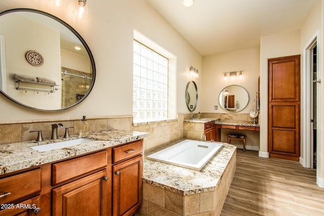 bathroom featuring hardwood / wood-style flooring, vanity, and a relaxing tiled tub