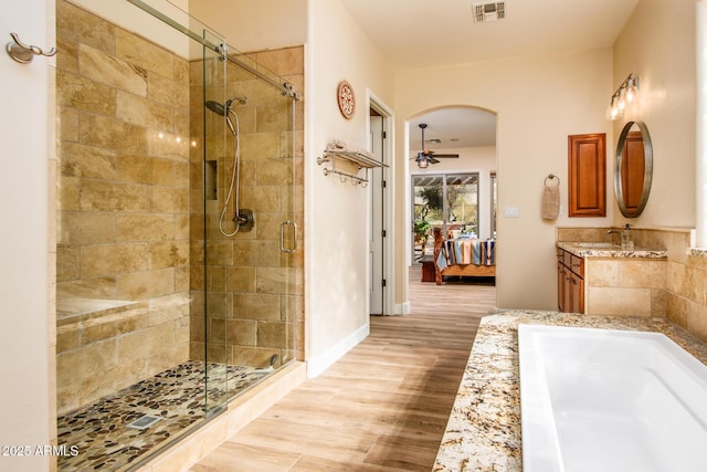 bathroom with wood-type flooring, separate shower and tub, vanity, and ceiling fan