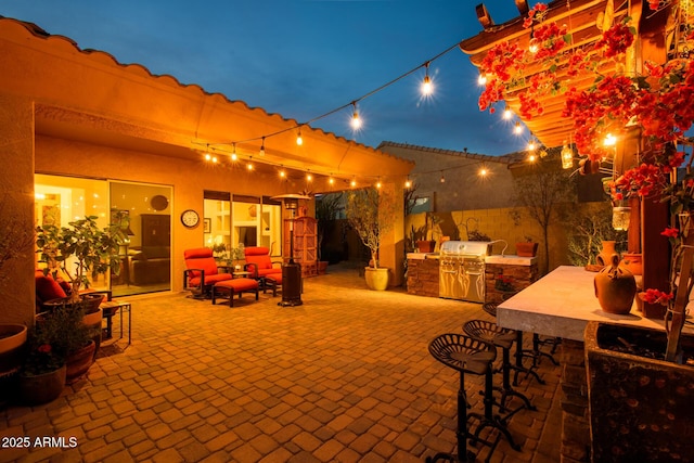 patio at night with area for grilling and exterior bar