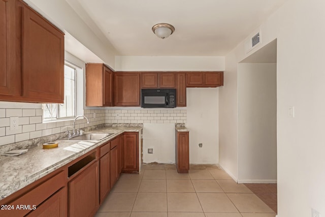 kitchen with decorative backsplash, light tile patterned floors, light stone countertops, and sink