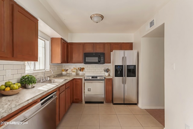 kitchen featuring appliances with stainless steel finishes, backsplash, light tile patterned floors, and sink