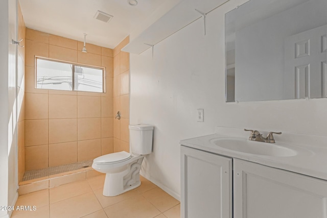 bathroom with tile patterned floors, vanity, a tile shower, and toilet