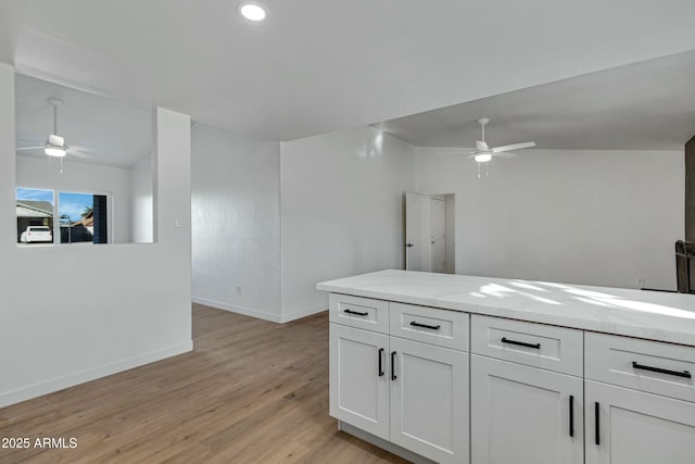 kitchen featuring light stone counters, ceiling fan, light hardwood / wood-style floors, and white cabinets