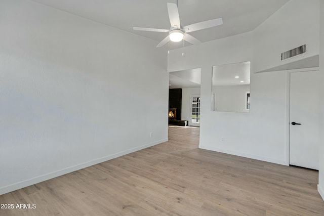 unfurnished room with ceiling fan, vaulted ceiling, and light wood-type flooring