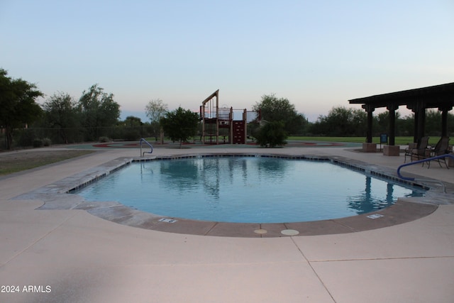 pool at dusk featuring a patio