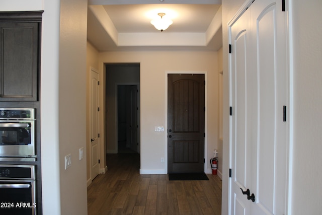 hallway with a raised ceiling and dark hardwood / wood-style flooring