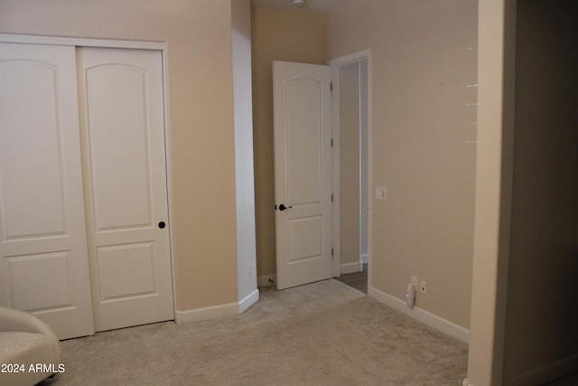 unfurnished bedroom featuring light carpet and a closet