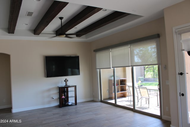 unfurnished living room featuring beam ceiling, ceiling fan, and light hardwood / wood-style flooring