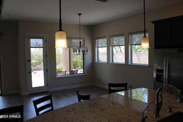 kitchen with light stone counters, pendant lighting, and stainless steel fridge