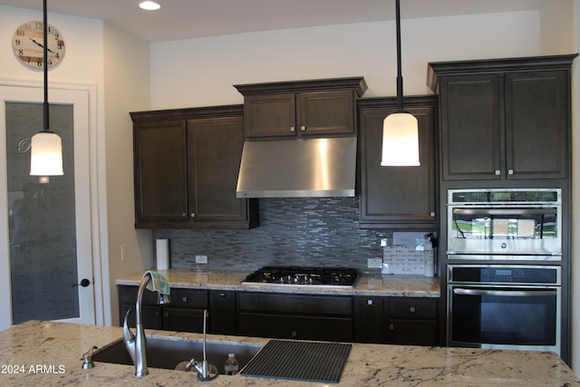 kitchen featuring pendant lighting, stainless steel appliances, backsplash, and ventilation hood