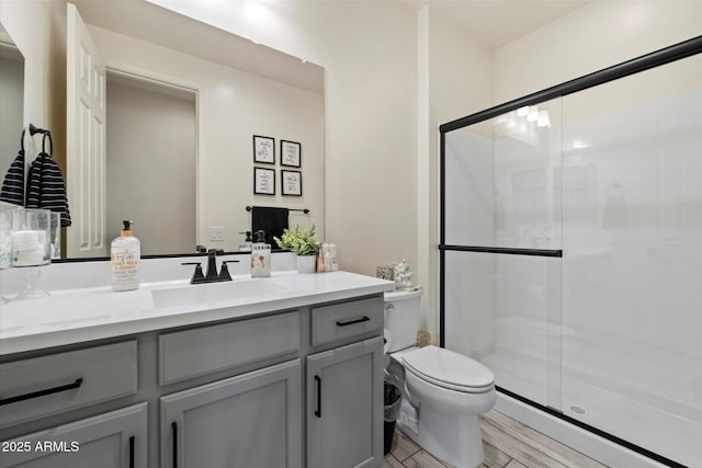 bathroom featuring baseboard heating, vanity, toilet, wood finished floors, and a stall shower