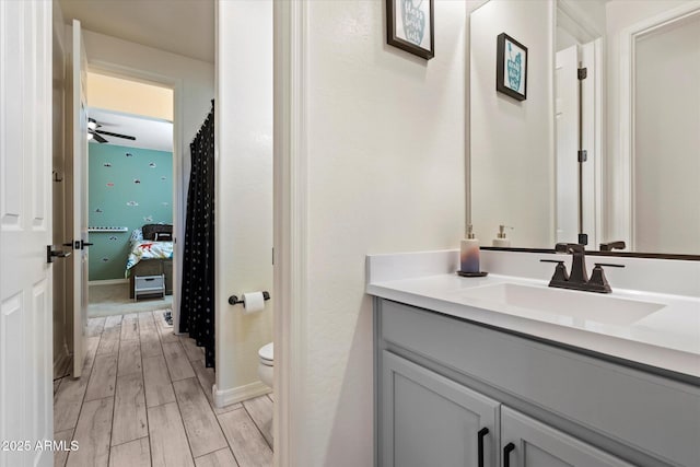 ensuite bathroom with a ceiling fan, wood finished floors, vanity, toilet, and ensuite bathroom