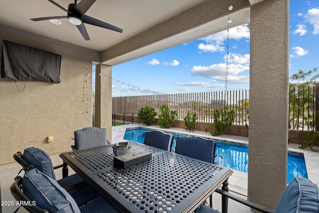 view of swimming pool with a fenced in pool, a fenced backyard, ceiling fan, and outdoor dining space