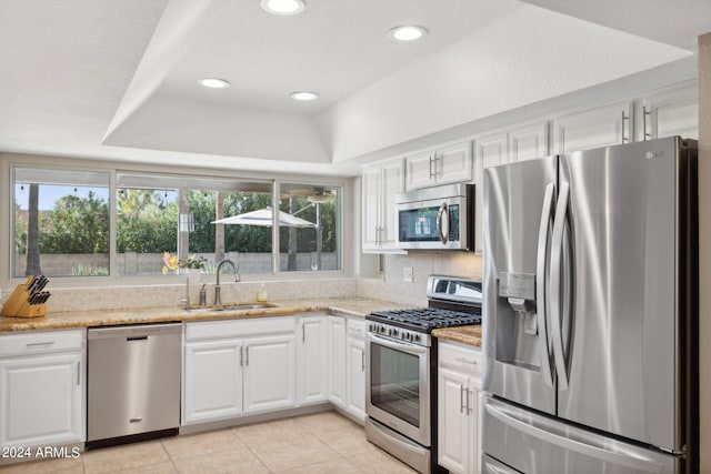 kitchen featuring a raised ceiling, white cabinetry, appliances with stainless steel finishes, and sink