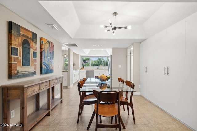 dining area with an inviting chandelier, a tray ceiling, light tile patterned flooring, and sink