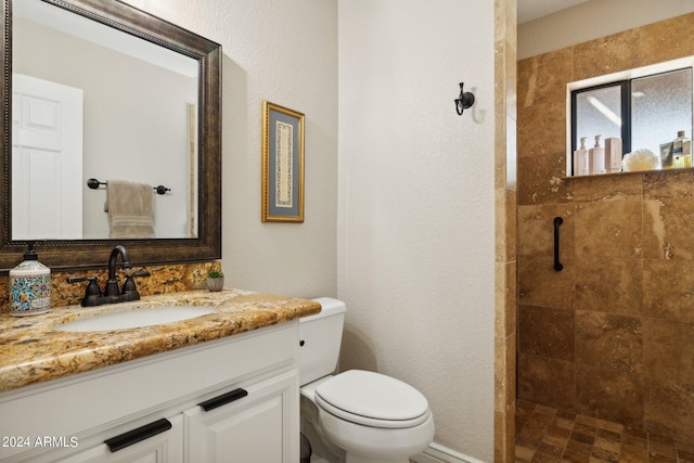 bathroom with vanity, tiled shower, and toilet