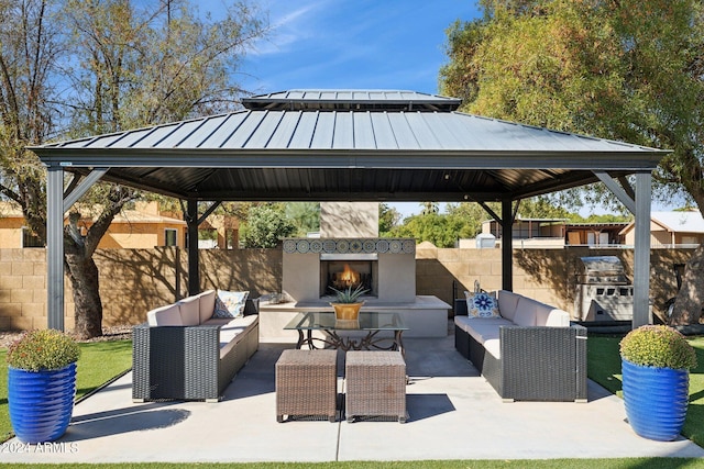 view of patio / terrace featuring a gazebo, an outdoor living space with a fireplace, and exterior kitchen