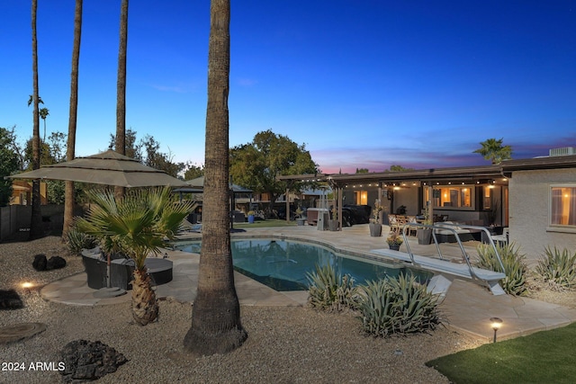 pool at dusk with a patio area