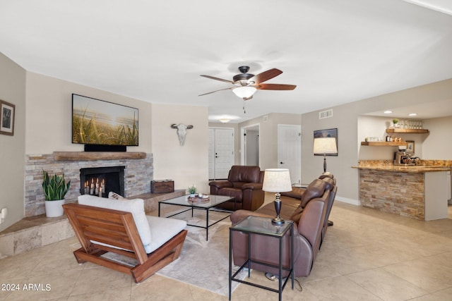 tiled living room featuring ceiling fan, indoor bar, and a fireplace