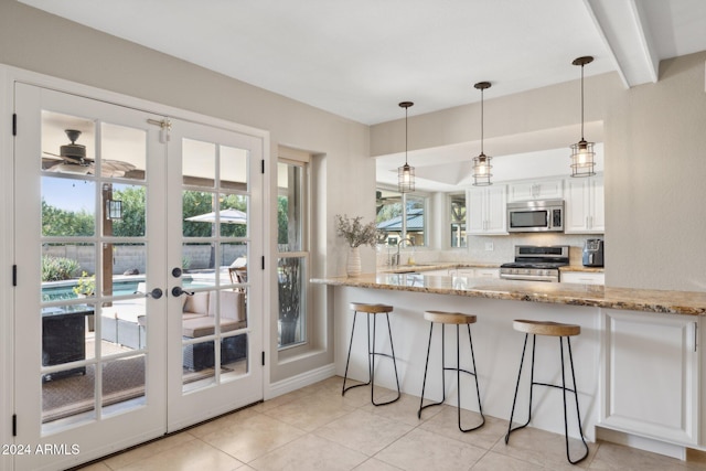 kitchen featuring sink, kitchen peninsula, stainless steel appliances, light stone countertops, and white cabinets