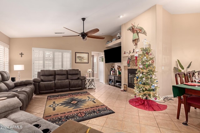 tiled living room featuring a tiled fireplace, ceiling fan, and lofted ceiling