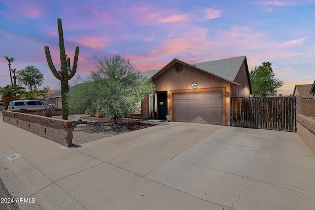 ranch-style house with a garage, fence, concrete driveway, and stucco siding